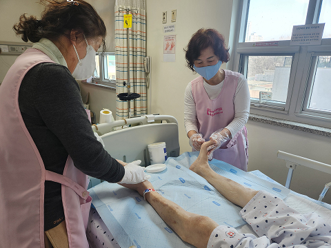 발마사지 봉사: 환자 한 분의 다리를 봉사자 두분이서 마시지 관리를 하고 있는 모습